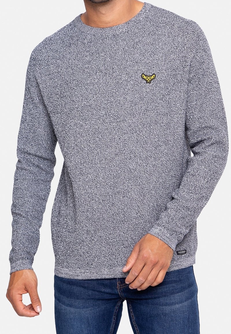 Grauer Pullover mit langen Ärmeln und strukturiertem Strickdesign. Verfügt über ein dezentes gelbes Logo auf der Brust sowie gerippte Bündchen und Saum.