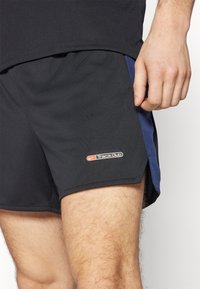 Shorts de sport noirs avec un panneau latéral bleu, texture en maille, et un logo blanc du Nike Track Club sur l'ourlet. Design sans coutures pour plus de confort.