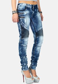 Jeans skinny in denim sbiadito blu con dettagli neri testurizzati e tasche con zip. Presentano dettagli a coste lungo le gambe.