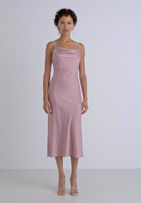 Satin roosa õhupüks koos õhukeste rihmadega, keskpõlve pikkuses, siledast tekstuurist ja lõdva istuvusega. Selged kontsad täiustavad riietust.