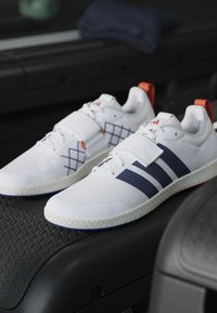 Biele športové topánky s námorníckymi pruhmi, štruktúrovanými bielymi prešívaniami, výraznými pätkami a unikátnym vzorom na podrážke.