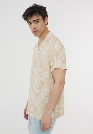 Camicia beige a maniche corte con un motivo di foglie di palma bianche, vestibilità comoda, chiusura con bottoni e tessuto morbido e leggero.