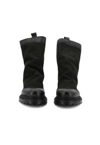 Stivali ankle neri con una punta in pelle liscia e una tomaia in morbido suede testurizzato. Presentano un pratico pull tab sul retro e una suola spessa in gomma.