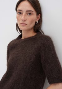 Pull en mélange de mohair brun avec des manches courtes et un large décolleté, présentant une texture douce et duveteuse ainsi qu'une coupe légèrement ample.