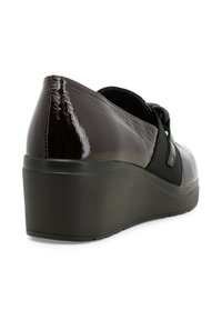 Scarpa con tacco a cuneo in vernice nera con fascia elastica, punta rotonda e superficie texture. Presenta una suola spessa in gomma nera.