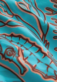 Tyrkysová tkanina s hladkou texturou, zdobená hnědými motivy chobotnic a mořských koníků, s důrazem na složité linie a vzory.