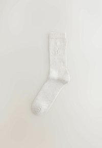 Hellgraue, gerippte Socke mit abgerundeter Spitze, gepolsterter Sohle und dezentem Logo-Detail nahe dem Knöchel. Aus Baumwollmischung.