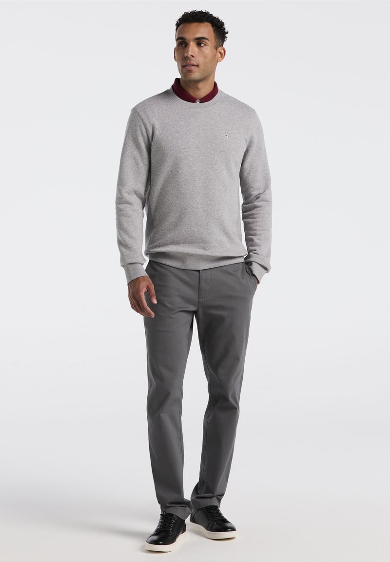 Lichtgrijze trui met een bordeauxrode kraag, gecombineerd met donkergrijze broek en zwarte sneakers. Eenvoudig ontwerp met elastische manchetten en tailleband.