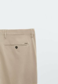 Pantaloni beige con fronte piatto, passanti per cintura e tasca posteriore con chiusura a bottone. Texture liscia e design casual.