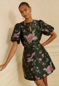 Rochie neagră cu imprimeu floral, cu mâneci scurte tip puff, guler cu decupaj, prezentând broderie multicoloră cu flori și păsări, textura netedă a satinului.