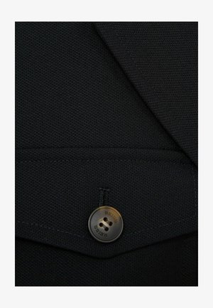 Black blazer fabric with a textured weave, featuring a rounded brown button with "REISS" engraved. Includes stitched detailing and flap pocket.