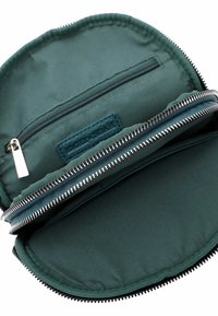 Donkergroene stoffen pouch met twee vakken met rits, een klein binnenzakje en zilverkleurige ritstrekkers, opengeklapt om de binnenkant te tonen.