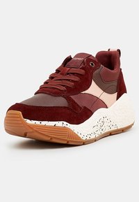 Baskets en daim rouge et mesh avec une semelle intermédiaire blanche tachetée et une semelle extérieure en gomme. Présente des accents marron foncé et des lacets épais.