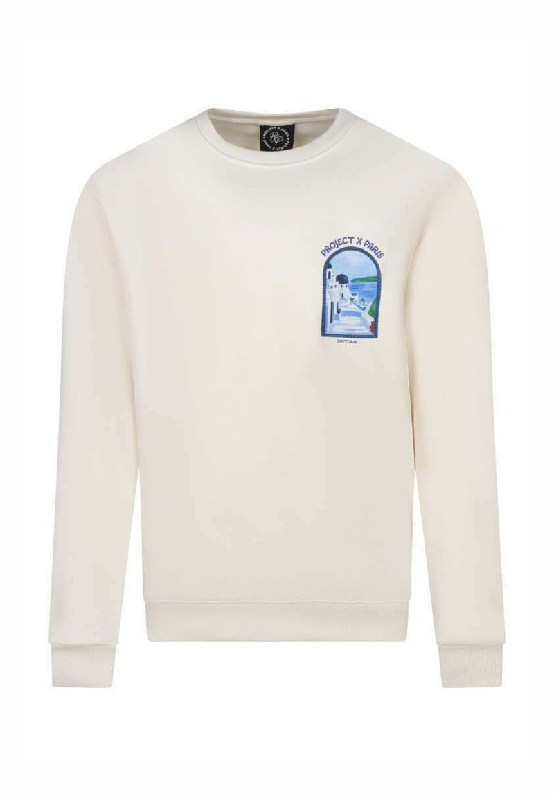 Sudadera de manga larga color crema con cuello redondo; presenta un parche gráfico colorido que representa una vista escénica en el lado izquierdo del pecho.