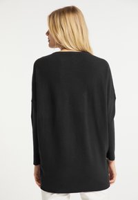 Maglione nero in maglia con una vestibilità ampia, caratterizzato da un collo rotondo e maniche lunghe. La texture è a coste e arriva fino ai fianchi.