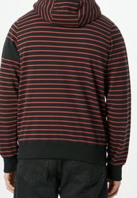 Sudadera negra con rayas rojas horizontales, puños y dobladillo acanalados, con capucha ajustable y tela suave y lisa. Se muestra vista trasera.