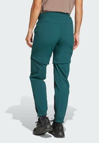 Teal hiking pants with adjustable waistband, elastic cuffs, and side pockets, made from lightweight, quick-drying material.
