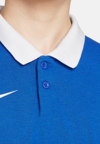 Polo shirt blu royal con colletto bianco, dotato di tre bottoni blu e un piccolo logo Nike bianco sul lato sinistro. Tessuto strutturato.