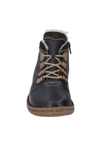 Bottine en cuir noir avec doublure crème, semelle brune texturée, lacets beiges et accents en cuir tan. Présente une fermeture éclair sur le côté.