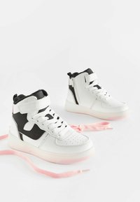 Adidași înalți din piele albă și neagră cu accente roz. Caracteristicile includ șireturi, curea Velcro, vârful perforat și talpa texturată.