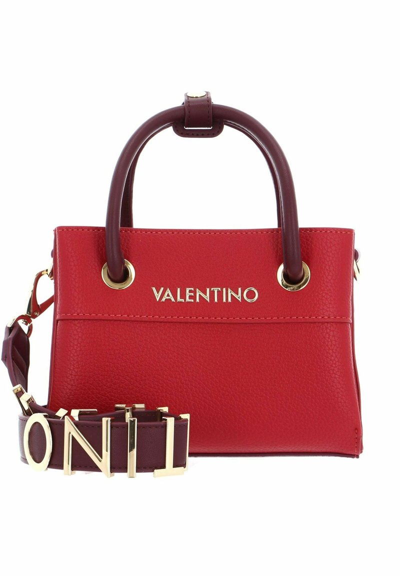 Red Valentino -laukkussa on tumma ruskea kahva, kultainen logo ja irrotettava hihna, jossa on suurilla kultaisilla kirjainyhdistelmillä kirjoitettu "VALENTINO."