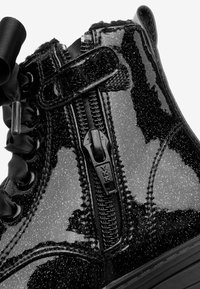 Kiilamattomasti musta kimalle ankle boot, jossa on sivuvetoketju, mustat satiininarut ja vetolenkki takana.