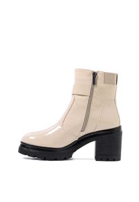 Stivale alla caviglia in pelle verniciata beige con zip laterale, accenti elastici, tacco chunky nero e suola texturizzata per una presa migliore.