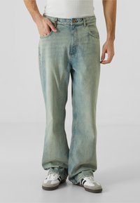 Vaaleansininen denim-farkut rentona istuvana, jossa on viisi taskua ja vetoketjukiinnitys. Kankaan väri on haalistunut ja siinä on hienovaraisia tekstuurivaihteluita.