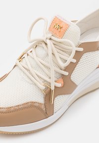 Sneaker con lacci che presenta una tomaia in rete bianca con dettagli in pelle beige, accessori in metallo dorato e un'etichetta logata arancione. Suole testurizzate per una buona aderenza.