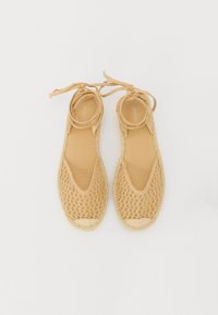Espadrillas beige con toma a rete e punta arrotondata. Presentano lacci alla caviglia e una suola in juta testurizzata per una maggiore aderenza e stabilità.