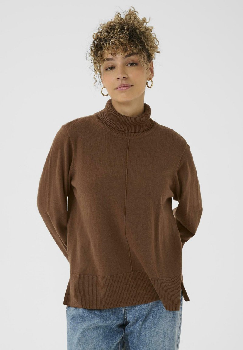 Brauner Rollkragenpullover aus weichem Strickstoff, mit seitlichem Schlitz und geripptem Saum, kombiniert mit hellblauen Denim-Jeans.