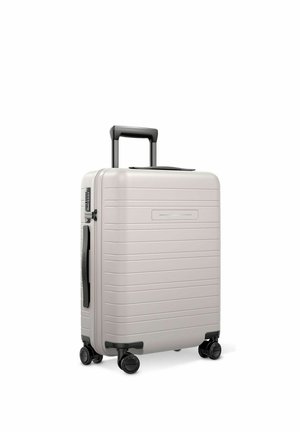 Hard-shell silver suitcase with black telescopic handle, side handle, four spinner wheels, and horizontal ridged design on a white background.