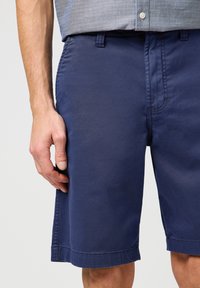 Granatowe bawełniane szorty o prostym kroju, z prostym wzorem pasa, bocznymi kieszeniami i widocznymi detalami przeszycia.