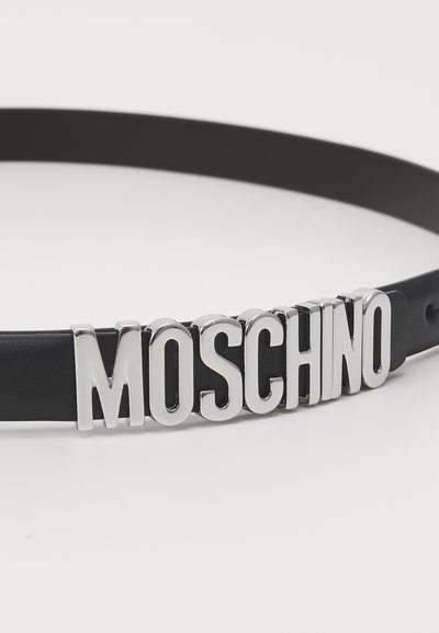 Fekete bőr öv, amelynek elülső részén hangsúlyos ezüst "MOSCHINO" logó található, sima textúrával és klasszikus csattalakíttal.