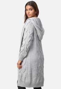 Cardigan lungo grigio lavorato a maglia con motivo a trecce, apertura frontale, maniche lunghe e cappuccio. I polsini e l'orlo a costine aggiungono texture e dettagli.