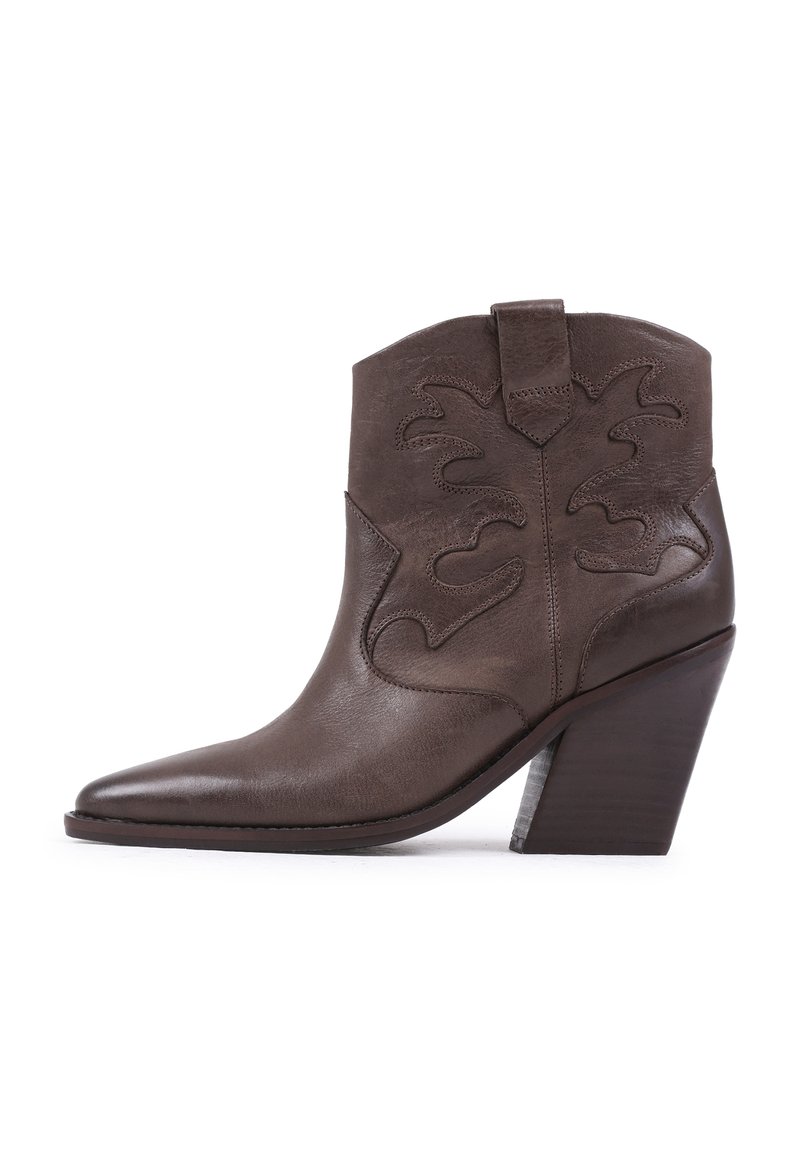 Bottine en cuir marron à bout pointu, avec des découpes décoratives sur la tige et un talon empilé, présentant une texture lisse.