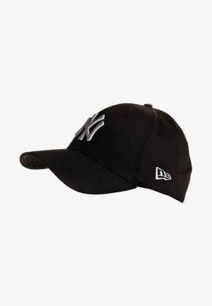 Sort baseballkasket med hvidt New York Yankees-logo foran og lille hvidt logo på siden, vist i en svag vinkel.