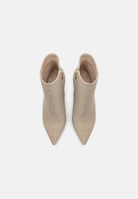 Paire de bottines beiges scintillantes à bout pointu avec fermetures éclair latérales, vue de dessus sur fond blanc.