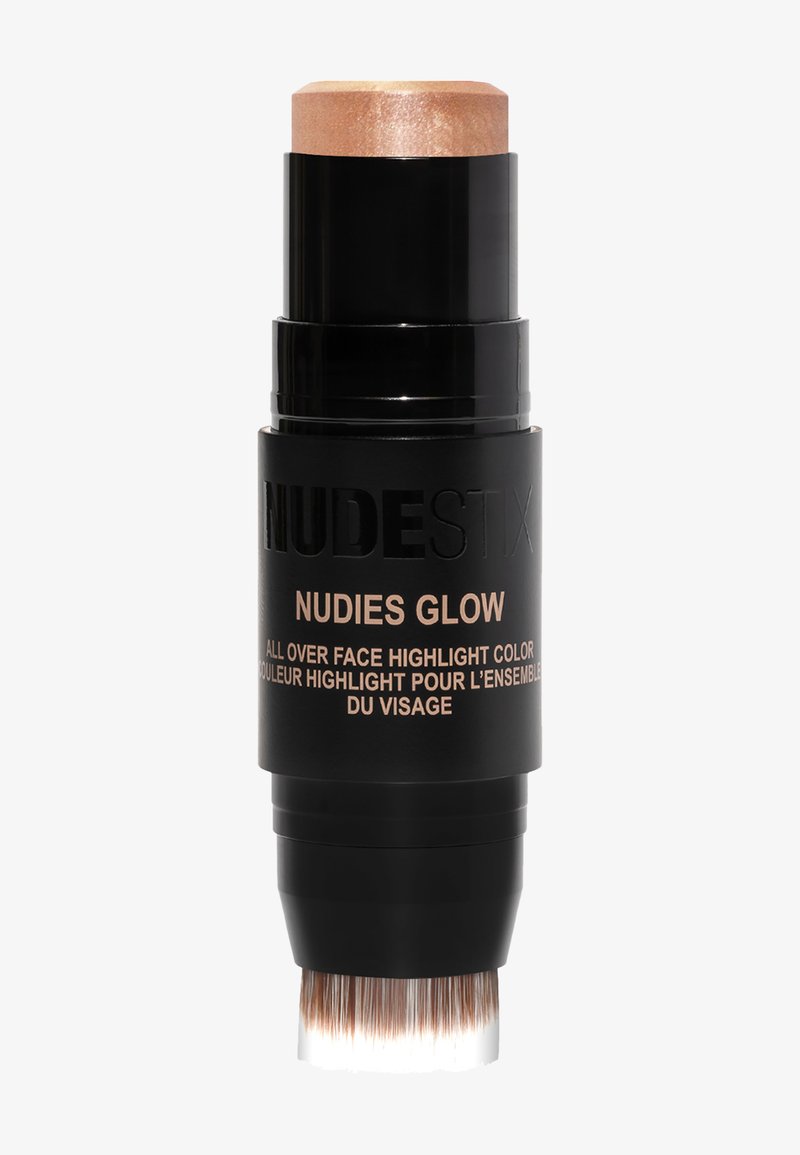 Marqueur en stick cylindrique noir avec un capuchon et une pointe de pinceau en or rose. Texte sur l'emballage en or indiquant "NUDIES GLOW" et les détails du produit.