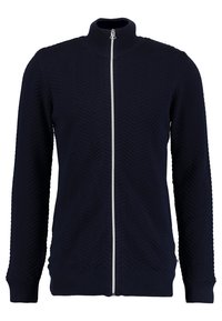 Marineblå hettejakke med høy krage, som har et teksturert fiskebeinmønster, ribbede mansjetter og liv, samt en sentral sølvglidelås.