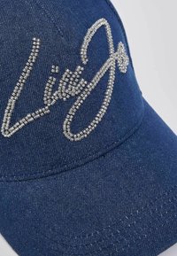 Casquette bleu denim ornée de strass argentés formant le texte « Lisa Jo » à l'avant, forme structurée avec une visière incurvée et des coutures décoratives.