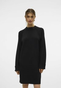 Schwarz Kleid mit langen Ärmeln, Rundhalsausschnitt und gerippter Textur. Verfügt über umgekrempelte Ärmel und eine lockere Passform. Einfaches und vielseitiges Design.