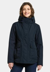 Marinblå vattentät jacka med huva, som har två framfickor, en dragkedja framtill och texturerad tyg för hållbarhet.