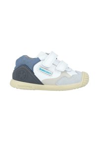 Scarpa sportiva bianca e grigia con cinturini in velcro, pannello in suede blu e suola in gomma con grip texturizzato. I dettagli includono un logo sul tallone.