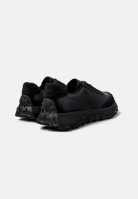 Black sneakers with a textured leather upper and suede accents. Low profile with a rugged rubber sole featuring a zigzag pattern.