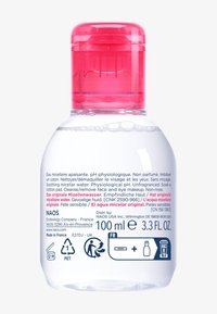 Bottiglia trasparente di micellar water con tappo flip-top rosa. Contiene 100 ml. Etichette in più lingue che descrivono l'uso e gli ingredienti.