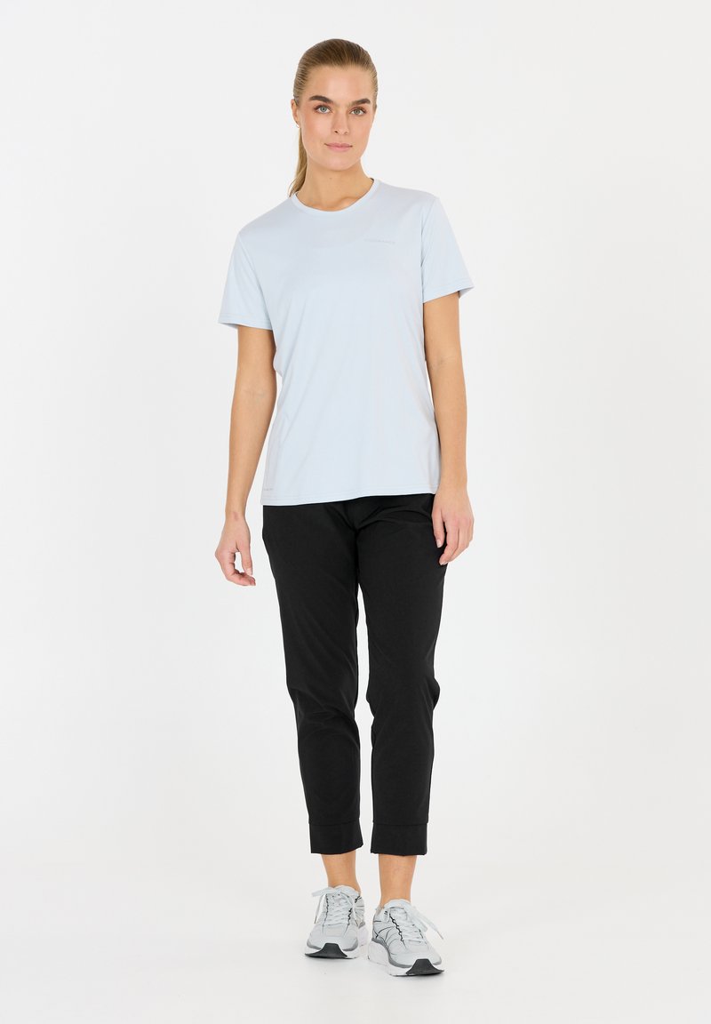 Ljust blå sportt-shirt med korta ärmar, ihop med svarta smala byxor och gråa träningsskor. Enkelt design, mjuk tygtextur.