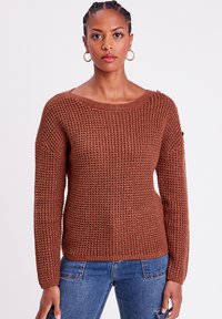 Pull en tricot marron avec un large col, des manches longues et un tissu texturé. Doté d'accents côtelés et d'une coupe décontractée.