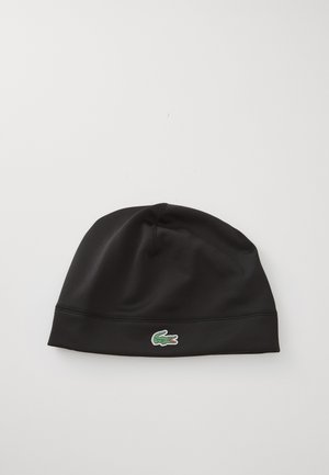 Zwarte beanie gemaakt van rekbaar materiaal met een gladde textuur. Voorzien van een groen krokodillenlogo aan de voorkant. Eenvoudig, naadloos ontwerp.