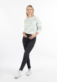 Világoskék mintás pulóver bordázott mandzsettákkal és alsó szegéllyel, fekete slim fit farmernadrággal és fehér, piros részletekkel ellátott sportcipővel párosítva.